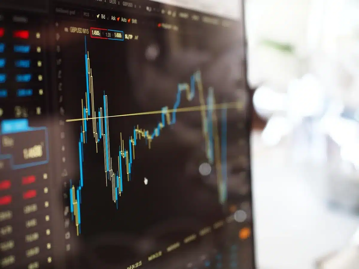 Close-up of hands holding a magnifying glass over a printed market chart showing falling lines, anonymous and unbranded