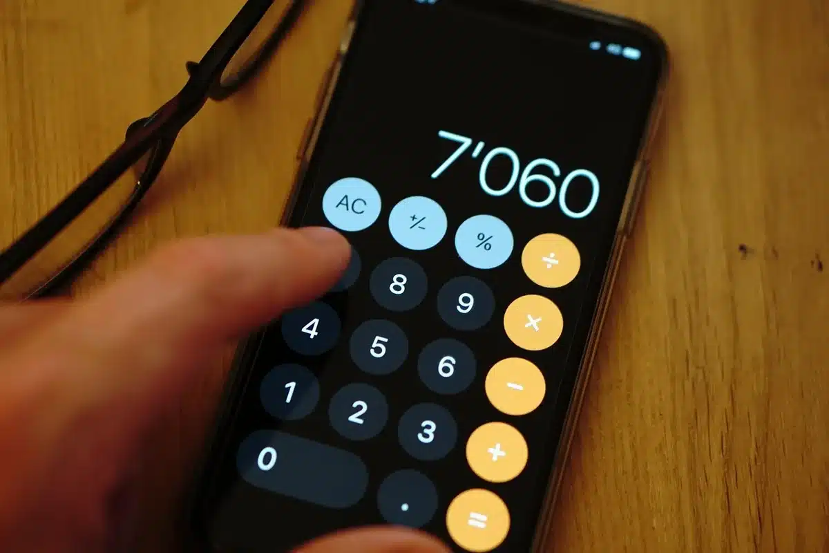 close-up of a desk with a calculator, ledger and a small unbranded gold coin in the background