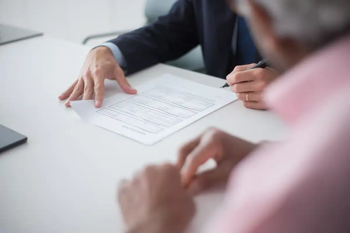 close-up of hands holding a few financial charts and a calculator on a desk, small blurred coins in the background
