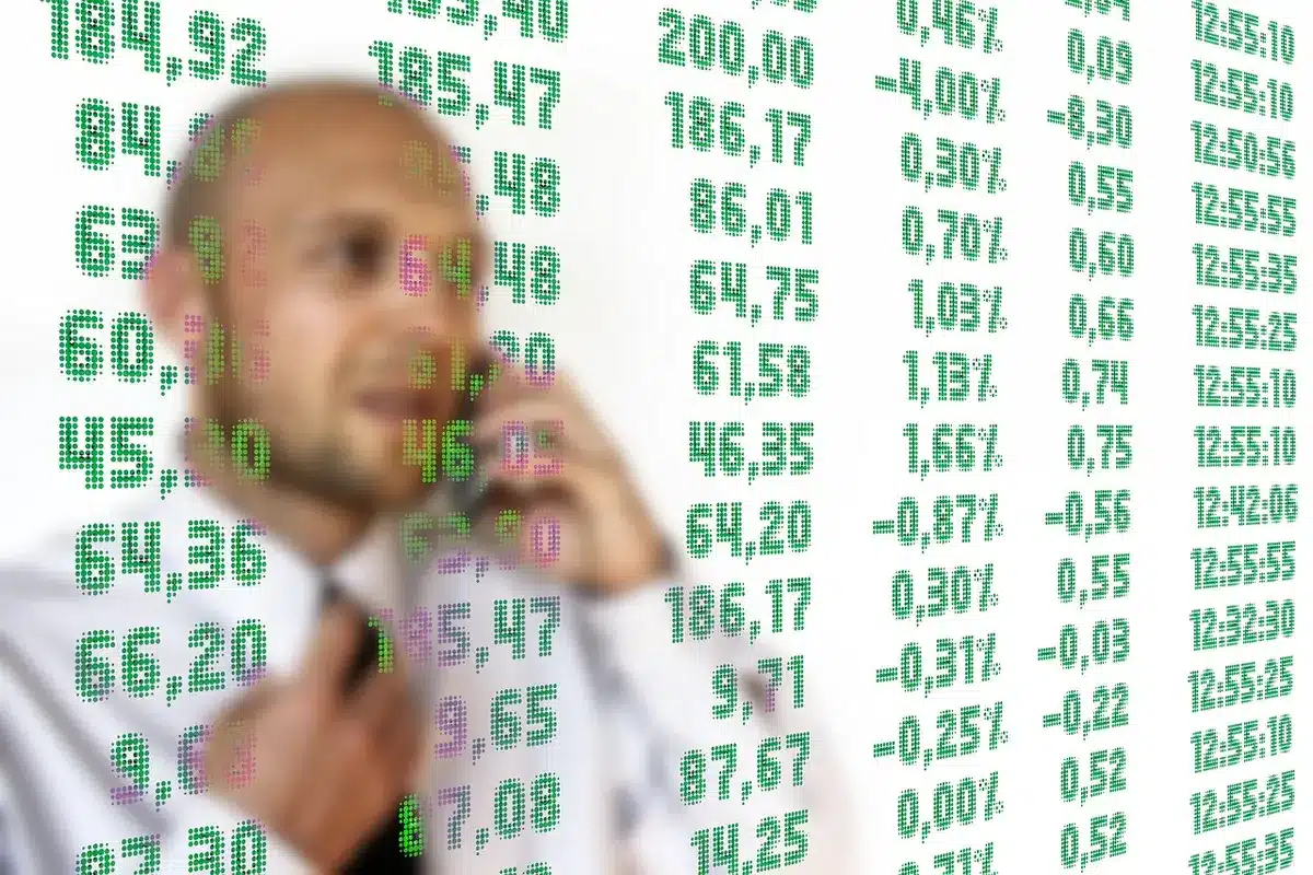 Neat office desk with a laptop showing a downward forex candlestick chart, a printed calendar showing October, and a cup of coffee to the side