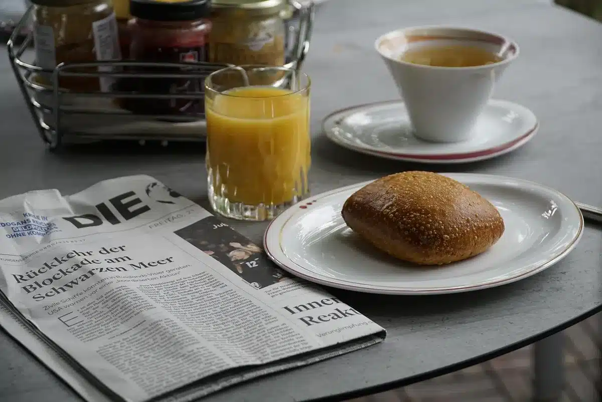 A neat desk with a financial newspaper open, a pen on top and an out-of-focus smartphone showing numbers in the background
