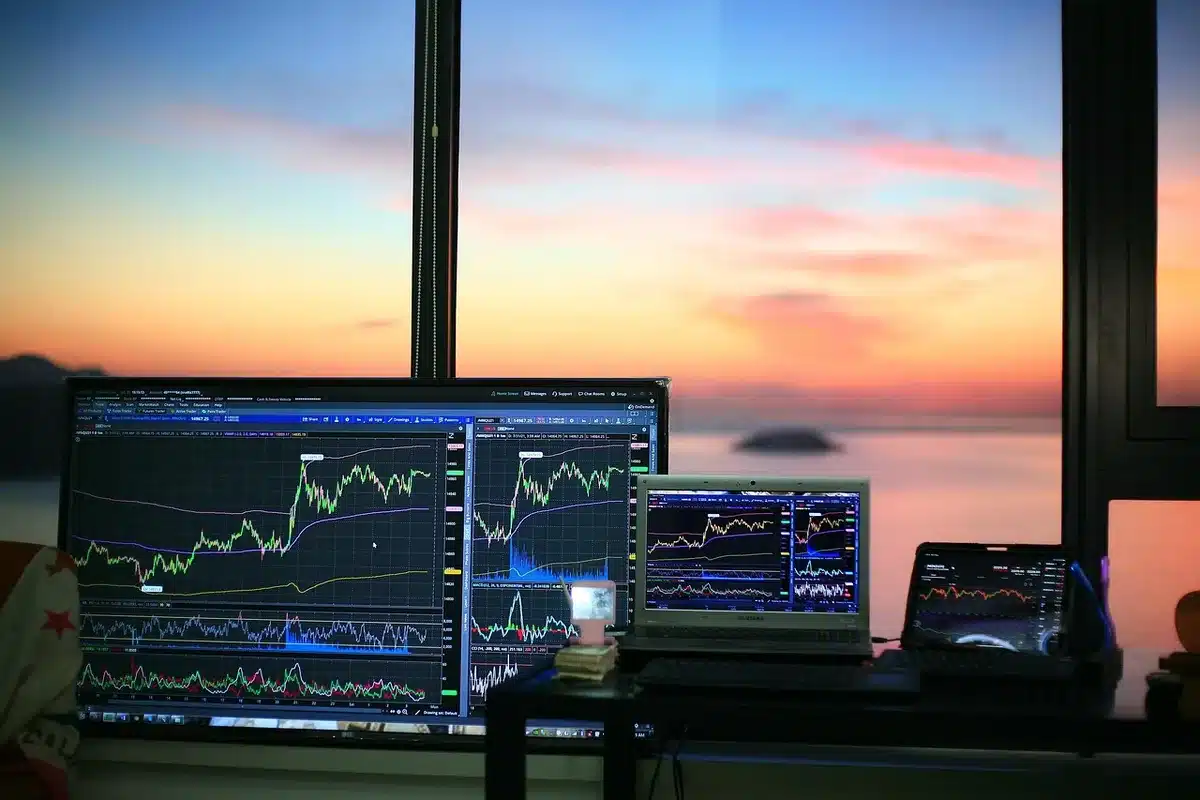 an empty trading desk with a muted gold bar in the background, laptop screen showing a falling chart