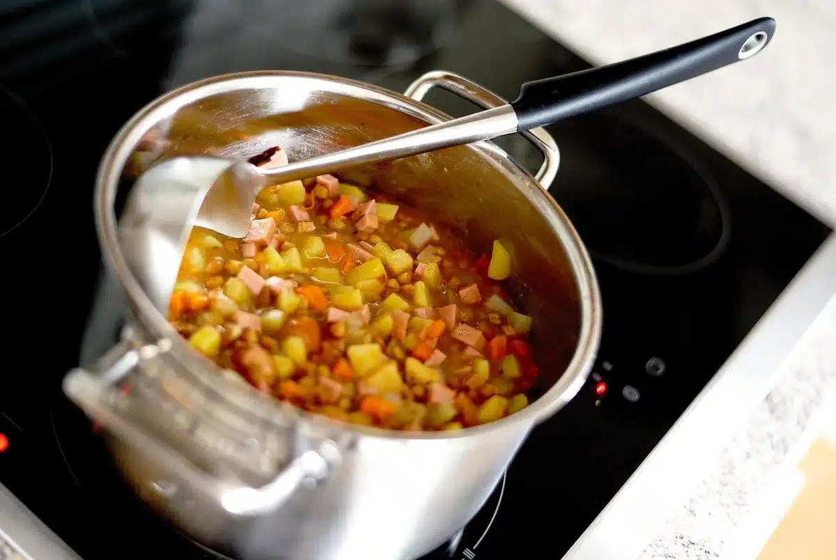 A simple bowl of cooked lentils beside a wooden spoon on a bright kitchen table, steam rising subtly