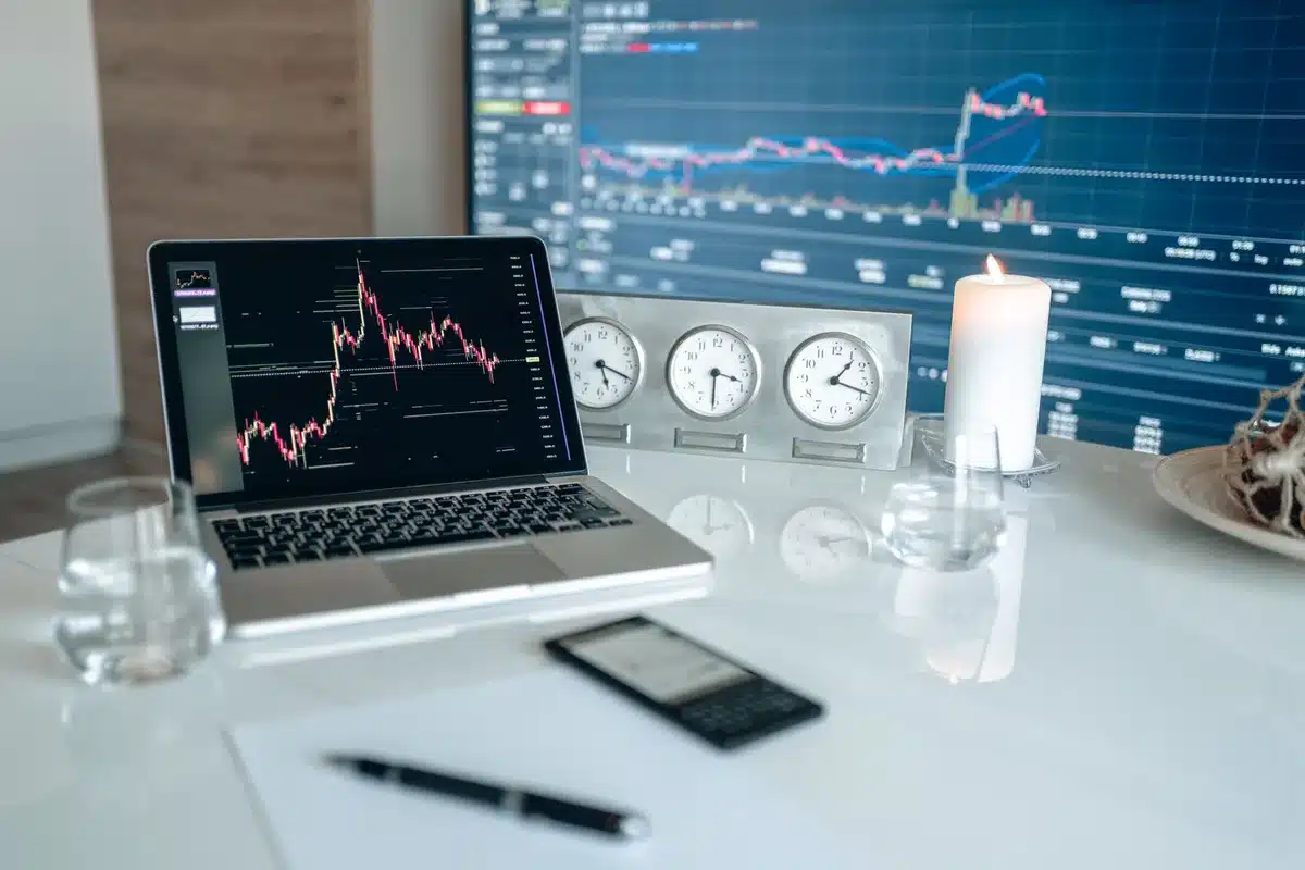 close-up of a trader's desk with price screens and a notepad